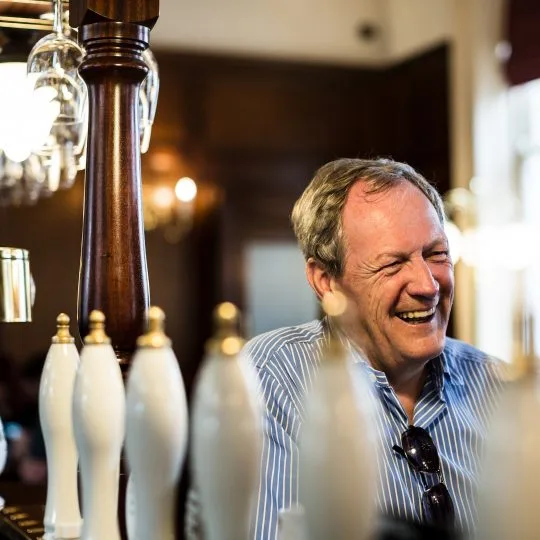 A customer laughing at the bar beside the white ceramic handpulls